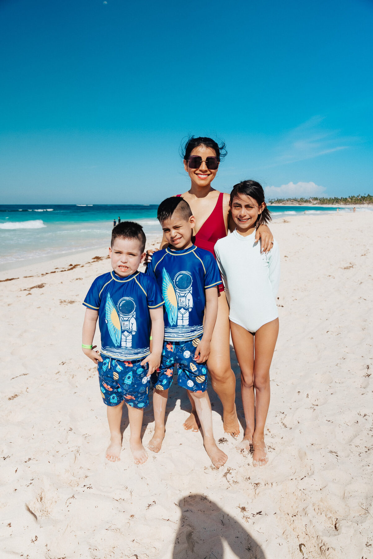Oliver with his mom, sister, and brother on a sunny beach.