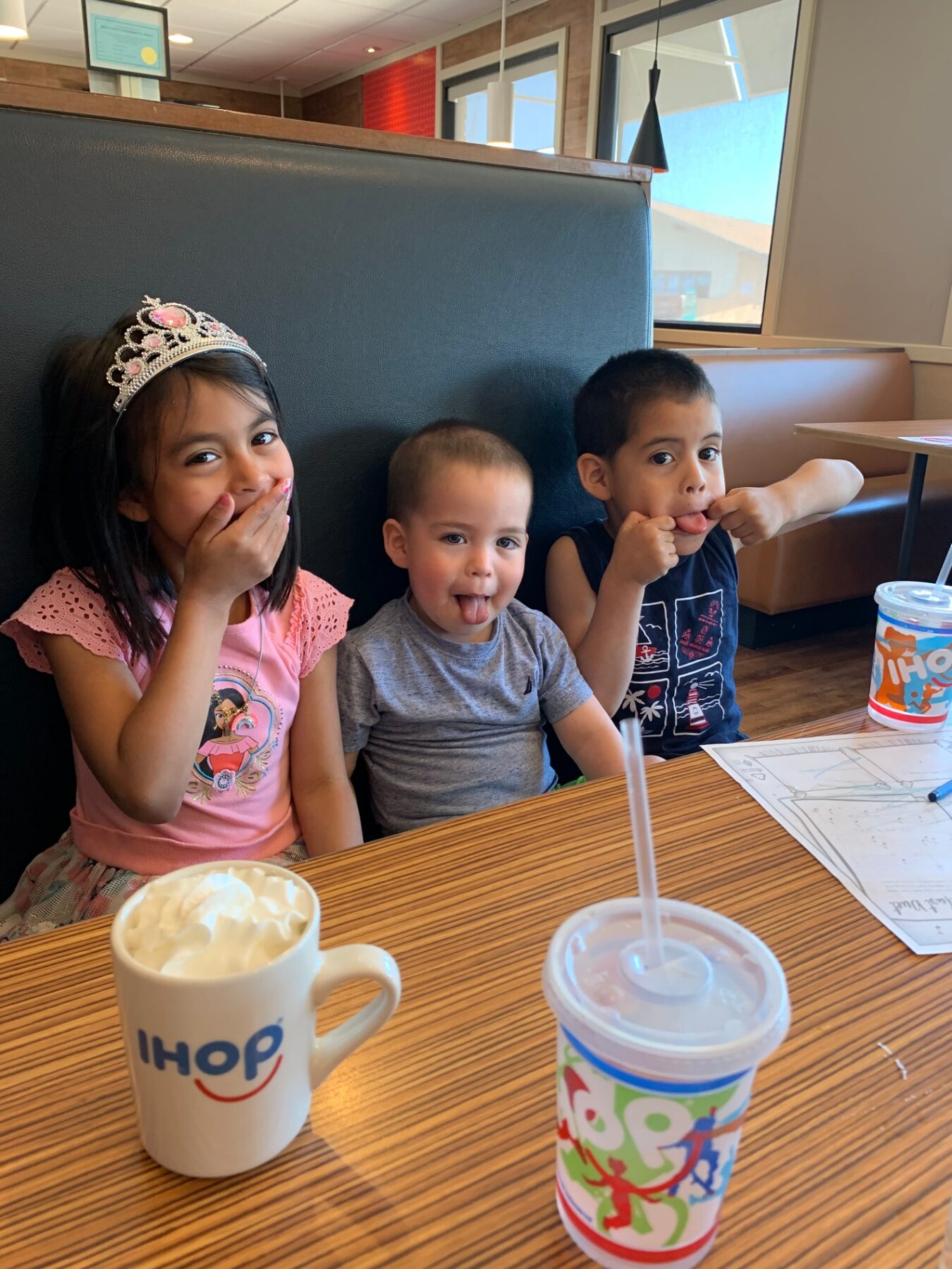 Young Oliver making a silly face with his sister and brother at breakfast.
